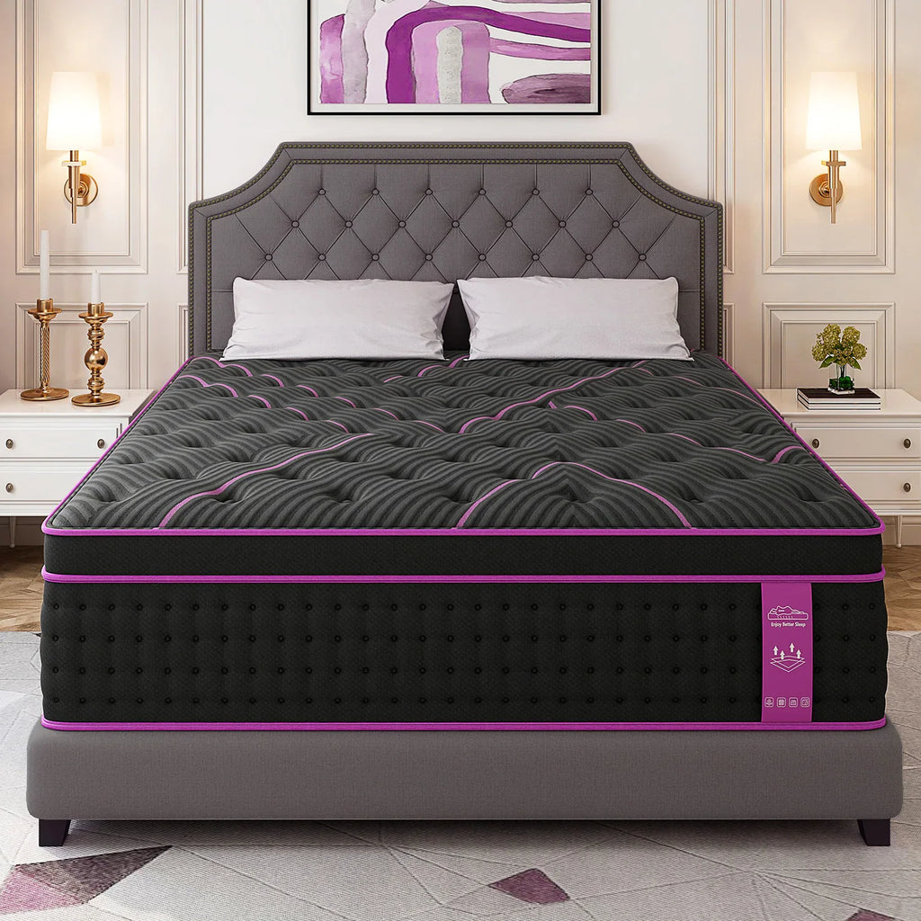 A thick hybrid mattress with a black and purple cover on a grey tufted bed frame.