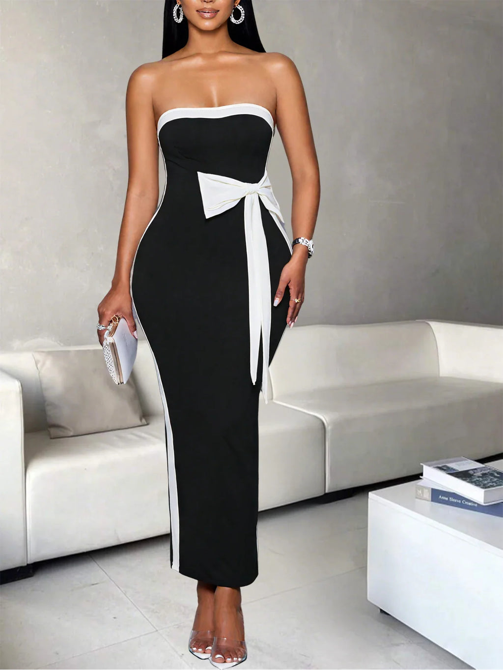 Woman wearing a black and white strapless midi dress holding a small clutch bag