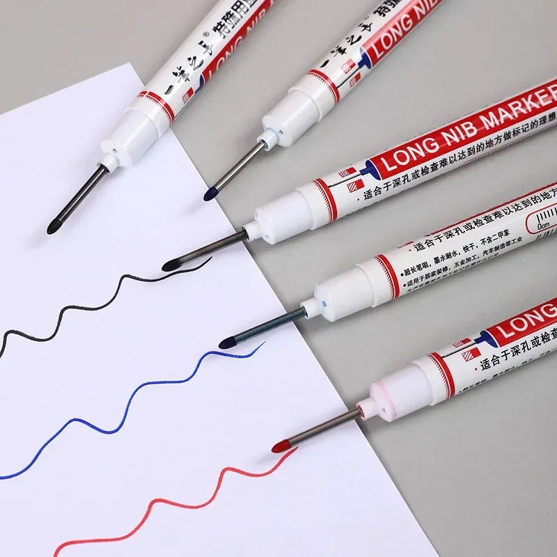 Several long nib markers in different colors being used to draw lines on a white sheet of paper.