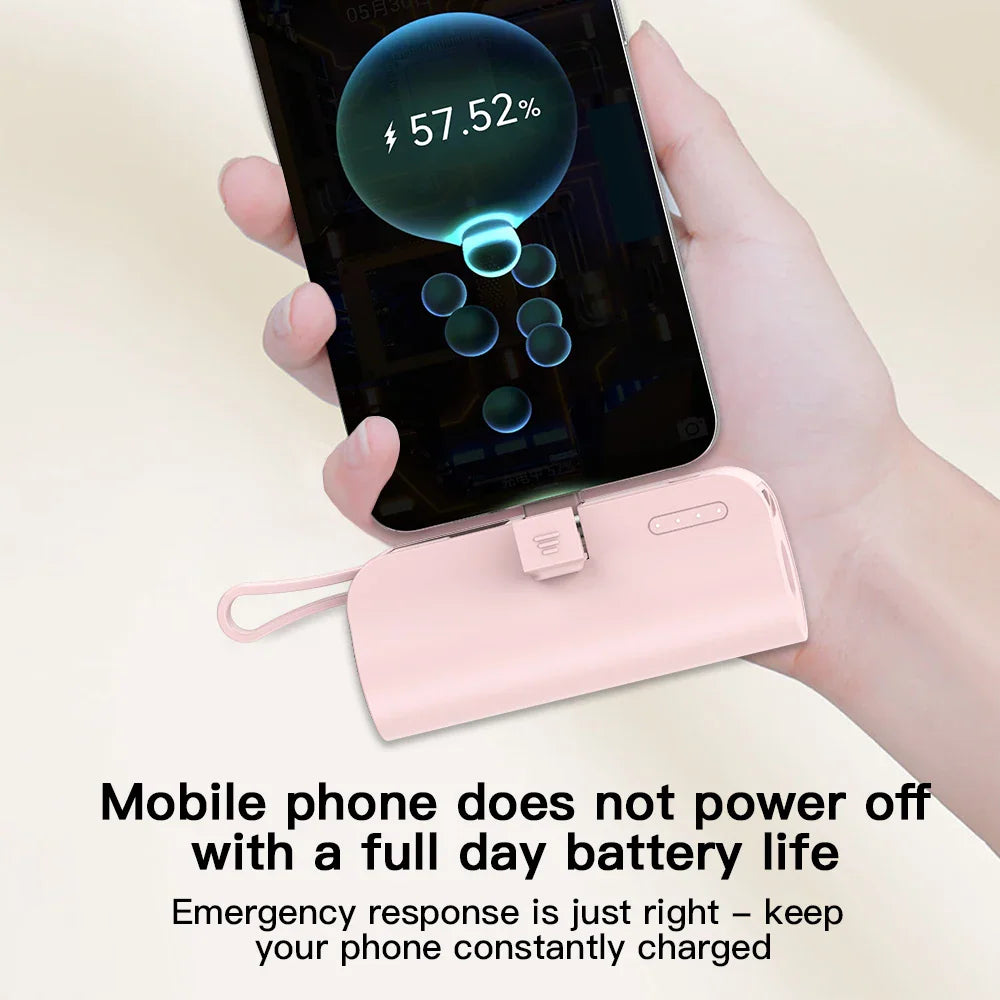 Hand holding a pink mini portable power bank plugged into a smartphone for emergency charging.