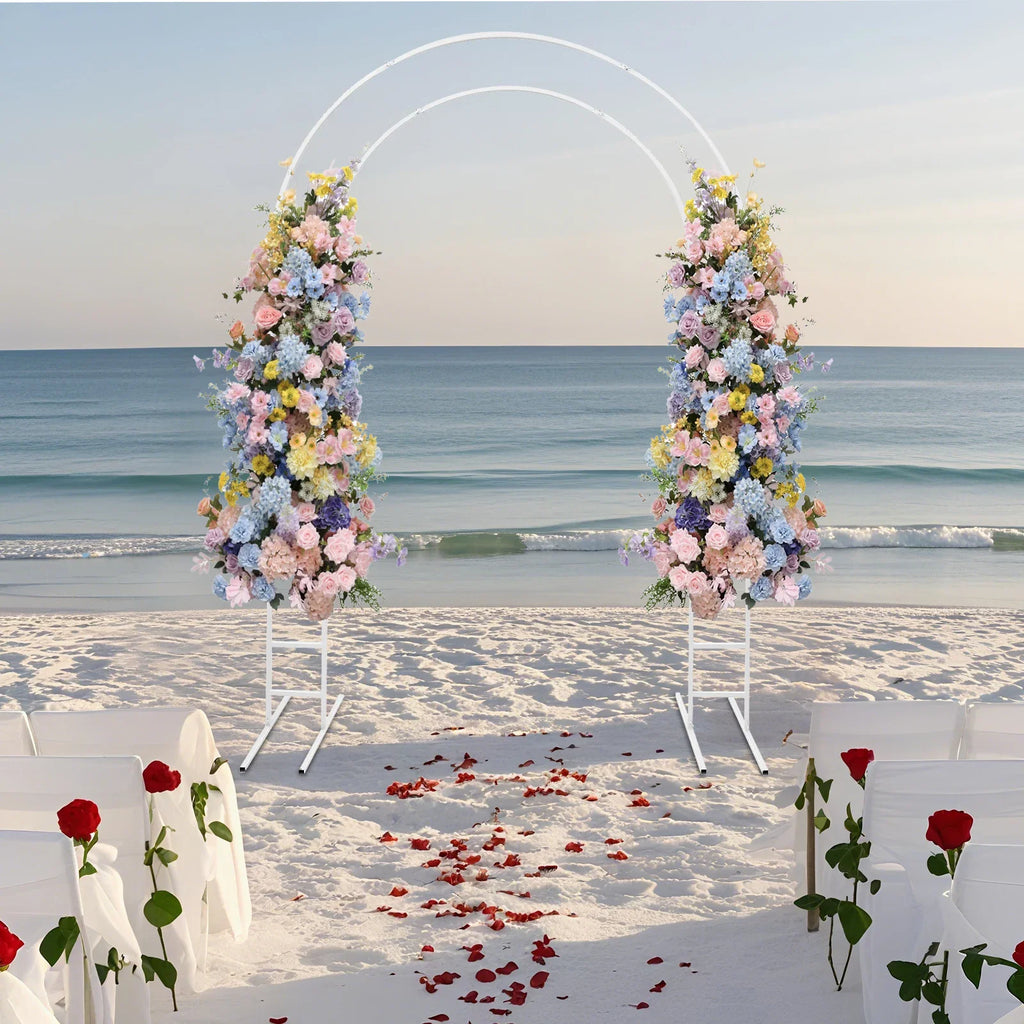 White metal round arch frame decorated with colorful flowers on a beach wedding aisle
