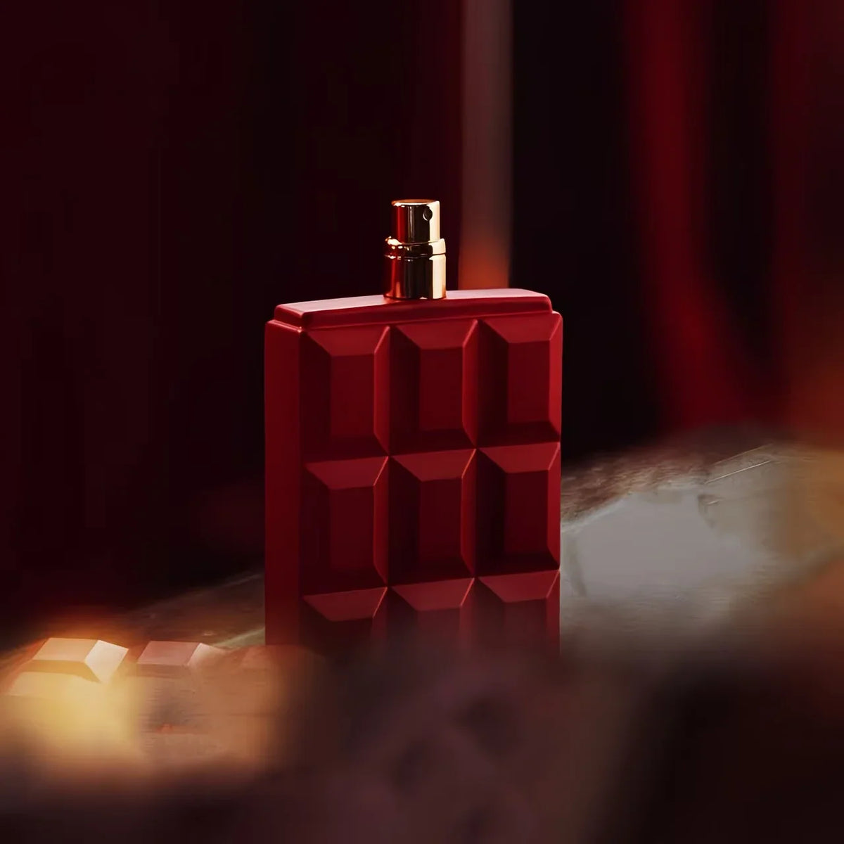 A red perfume bottle shaped like a chocolate bar set in a moody, dark, and romantic environment.
