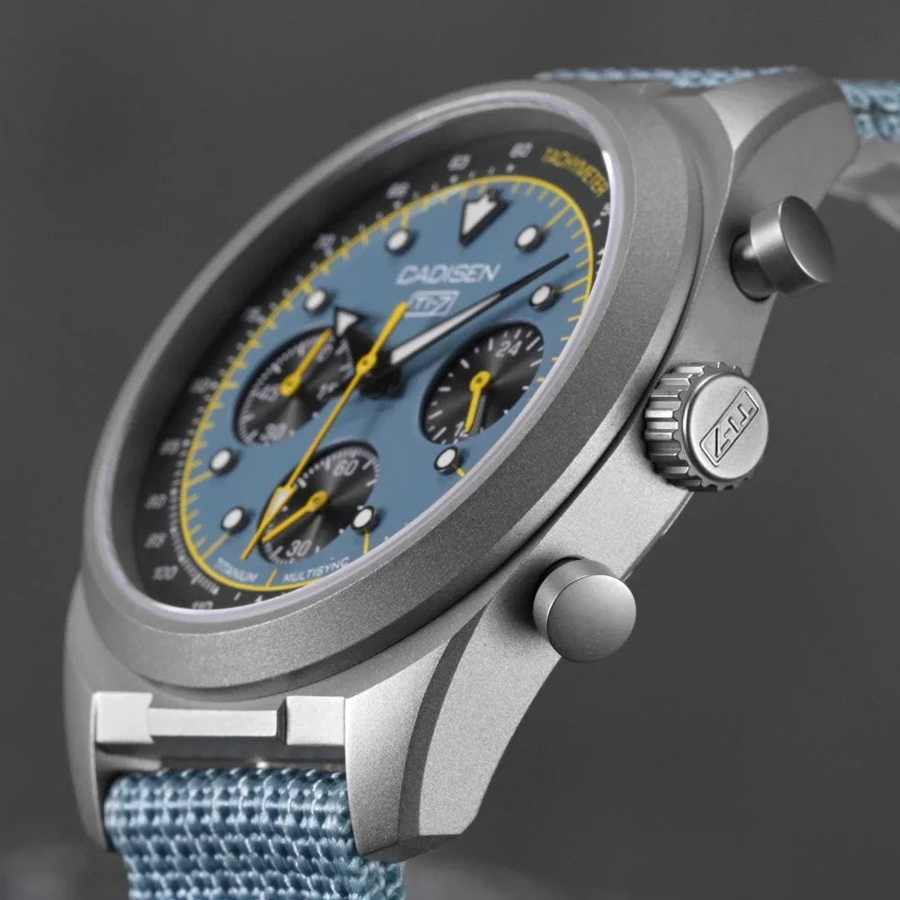 Side view of a blue dial chronograph watch with titanium case and light blue canvas strap