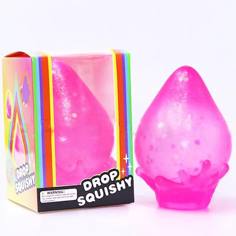 A single pink glittery water-drop squishy toy next to its rainbow-colored retail packaging box