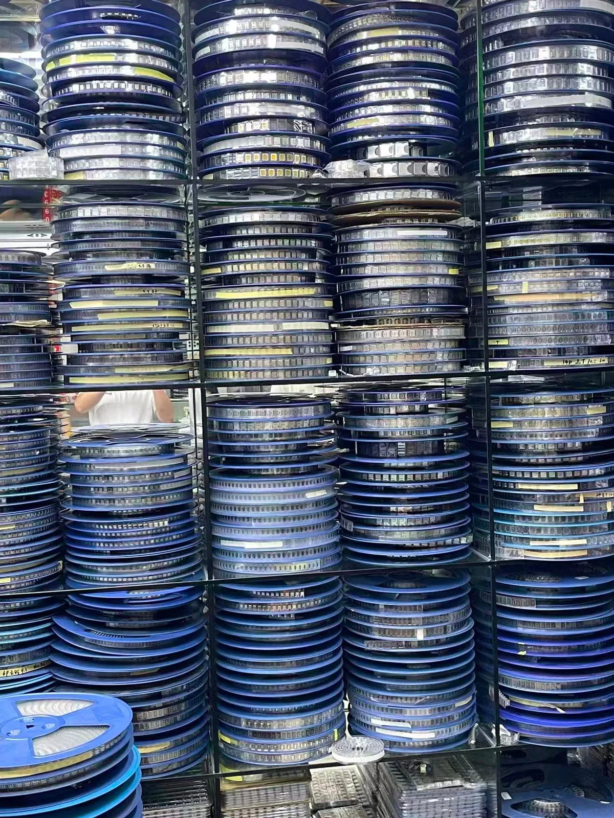 Shelves in a warehouse stacked with reels of electronic components for manufacturing.