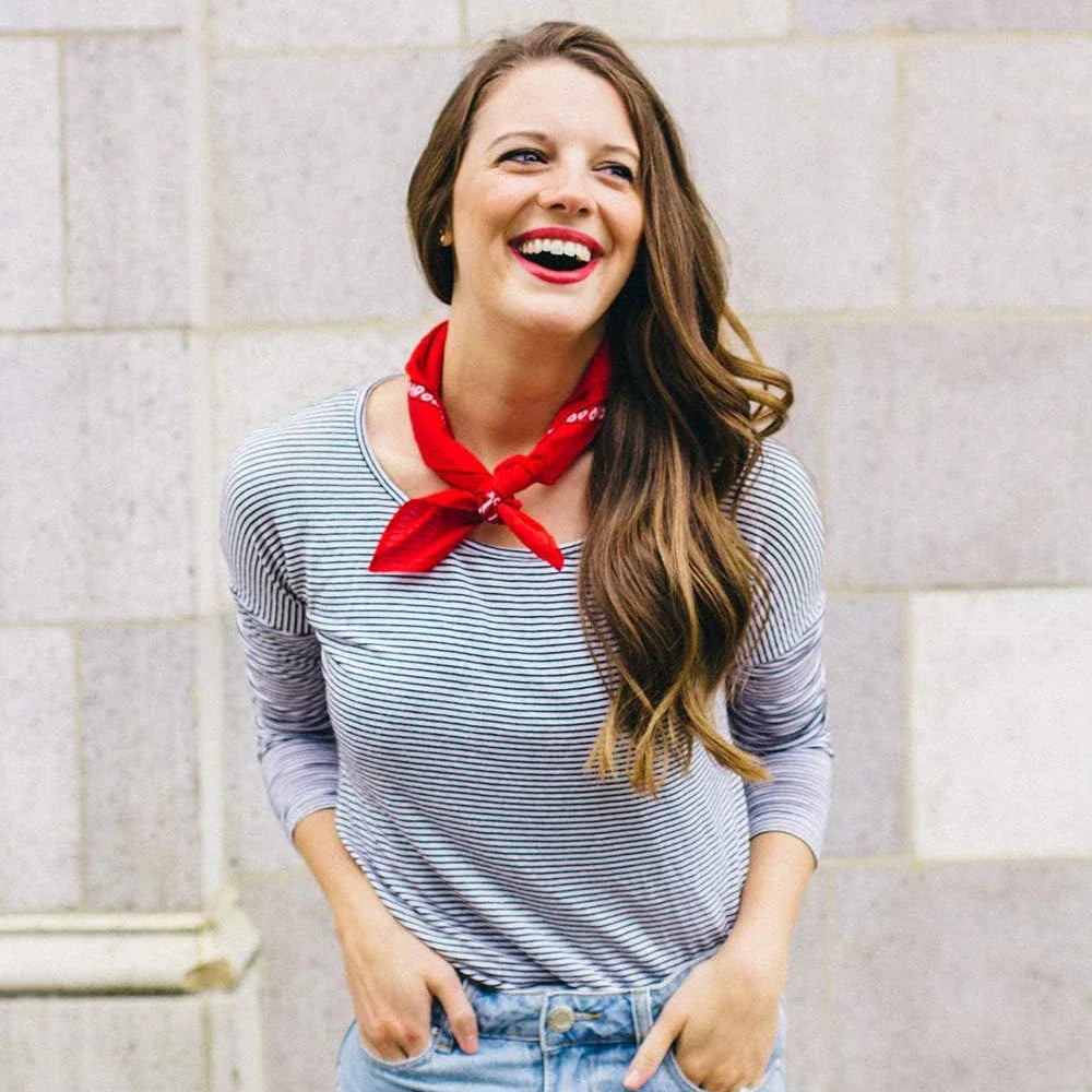 A woman wearing a red paisley bandana tied as a neck scarf.