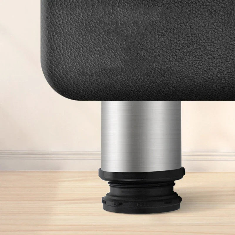 A stainless steel furniture leg attached to a piece of black leather upholstery