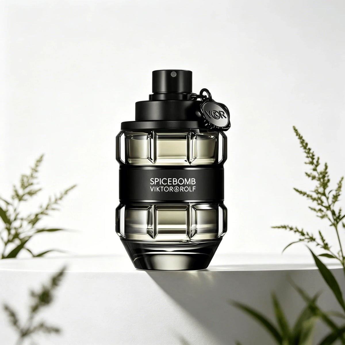 A glass perfume bottle shaped like a grenade, in a transparent black finish with a black band, on a white pedestal with