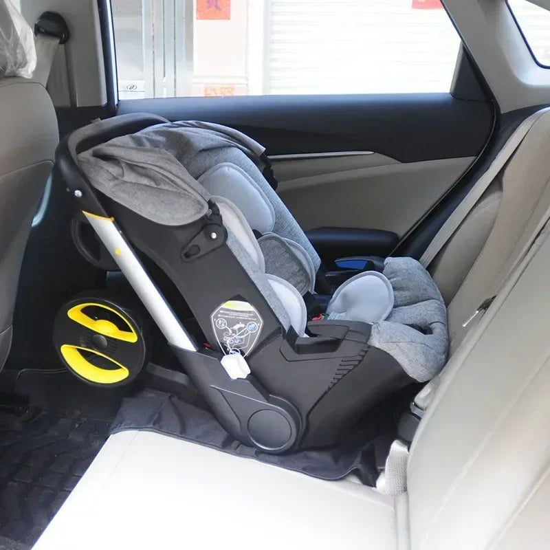 Grey infant car seat with wheels installed on a car passenger seat