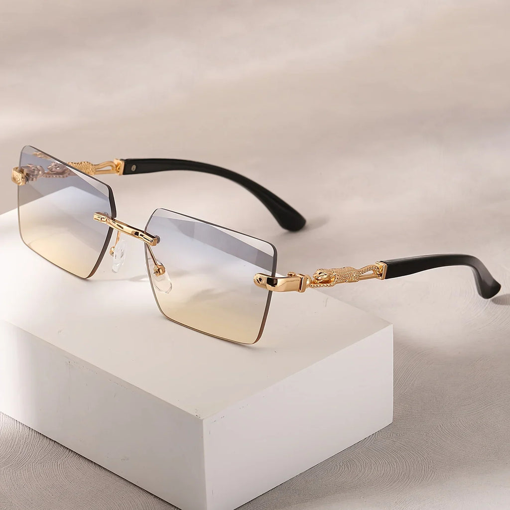 Rimless rectangular sunglasses with two-tone gradient lenses and gold panther-style metal temples on a white block