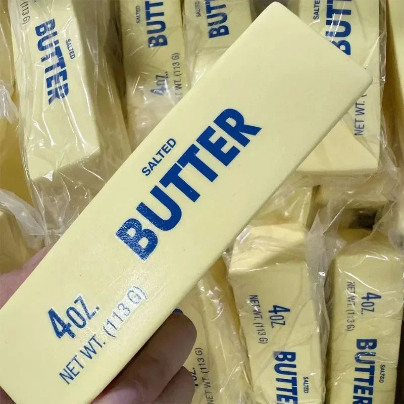 Squishy yellow butter stick fidget toy held in hand with many others in background