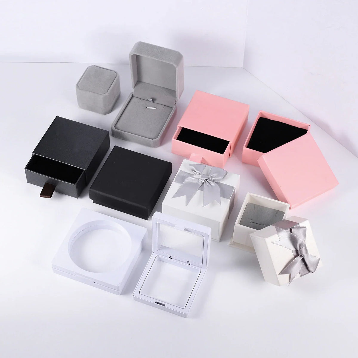 Various empty jewelry gift boxes in black, pink, grey and white with ribbons.