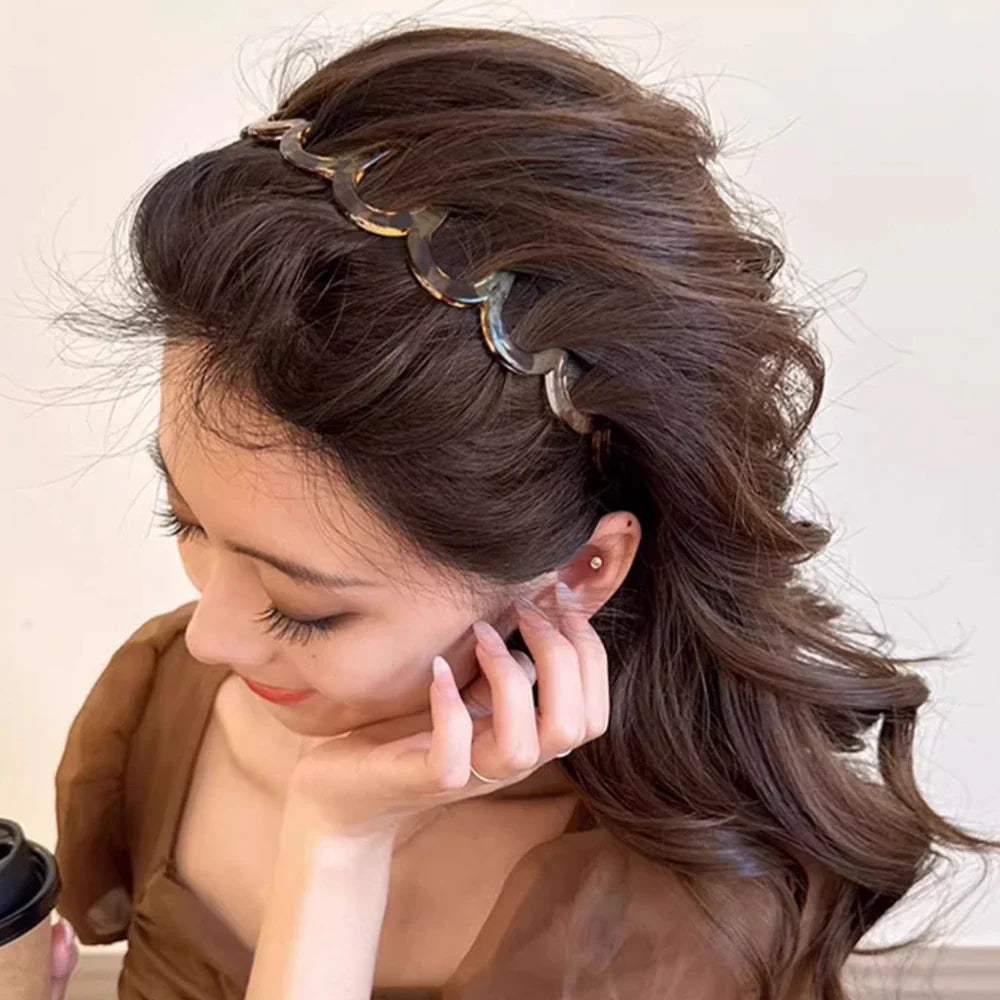 A woman wearing a scalloped tortoise shell pattern hair headband.