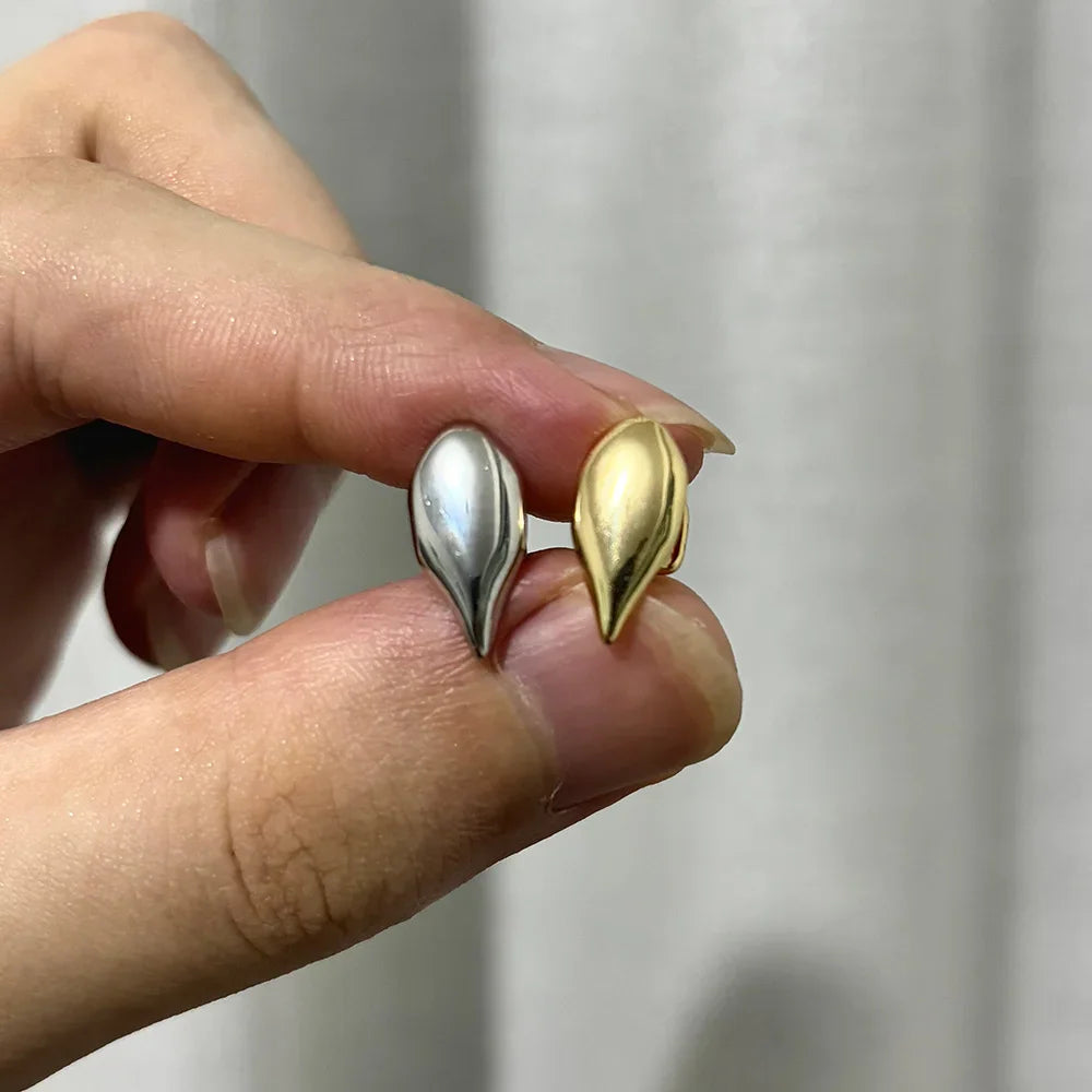 Hand holding a silver and a gold single vampire fang tooth cap