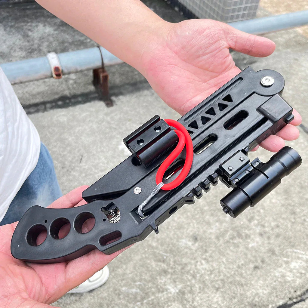 Foldable black hunting slingshot held in hand showing compact folded size
