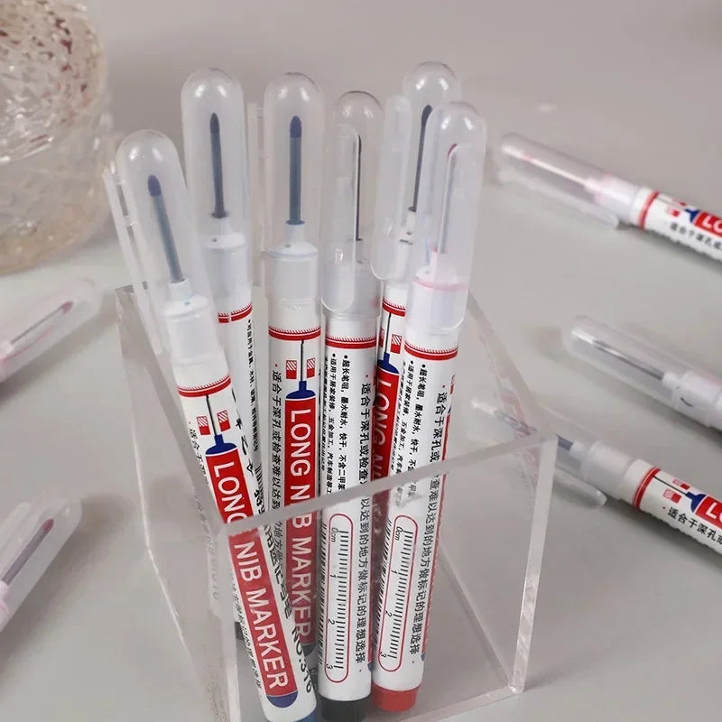 A set of long nib markers placed in a clear acrylic desk organizer holder.