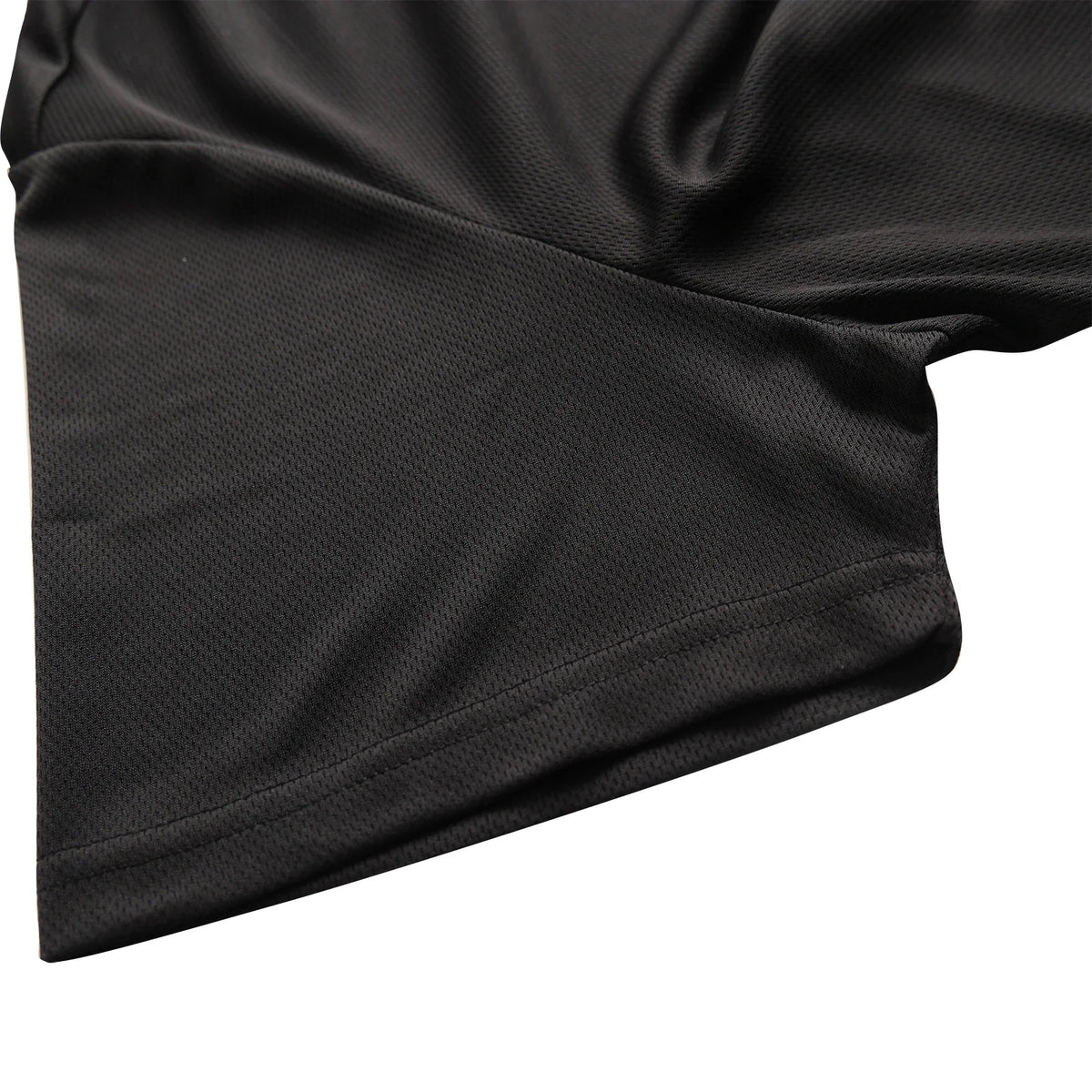 A close-up view of the sleeve hem of a black breathable polo shirt.
