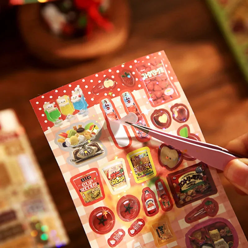 Close-up of a hand using tweezers to peel a decorative sticker from a sheet