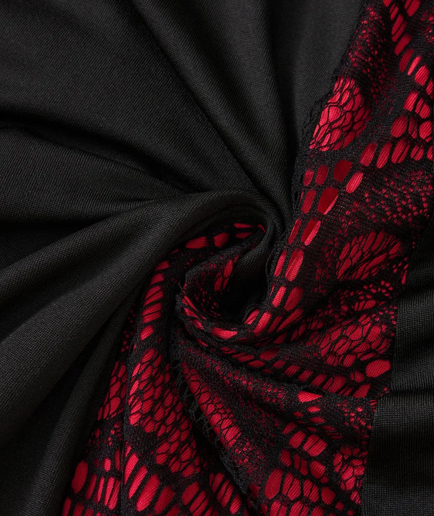 Detailed texture view of the red skull patterned lace and black fabric on a gothic style dress.