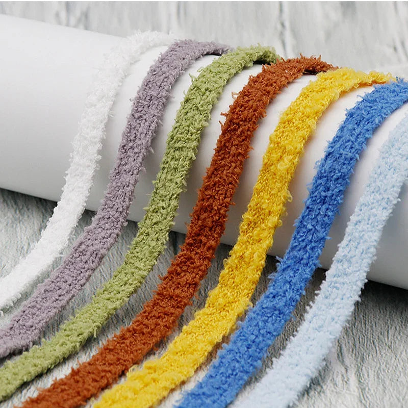 A close-up of several fluffy, multi-coloured plush shoelaces draped over a white cylindrical display.
