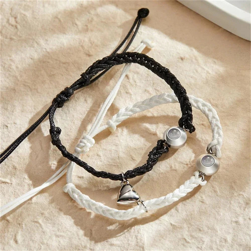 Black and white braided rope bracelets with central magnetic heart charms and projection beads