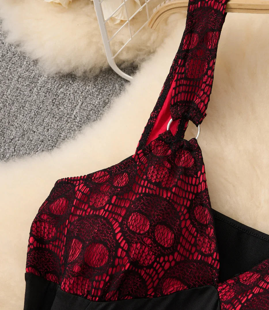 Close-up of the bodice and shoulder strap of a black and red gothic dress with skull lace and metal hardware.