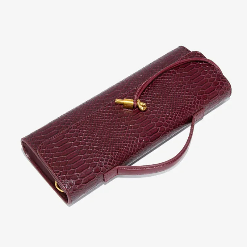 Dark red faux crocodile skin long clutch bag with a top handle and gold knot clasp