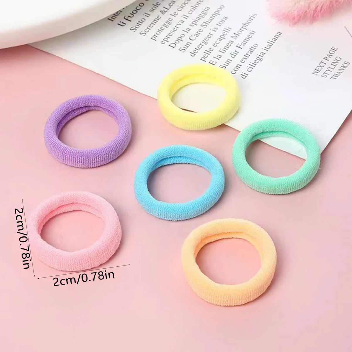 Small seamless fabric hair elastics in five pastel colors with size measurement overlay