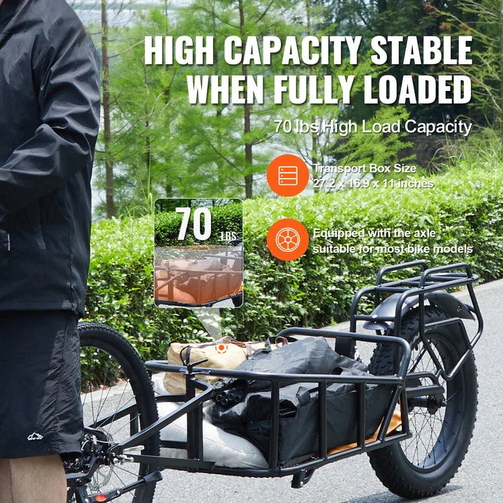 Black cargo bicycle trailer being used to transport gear in a park setting