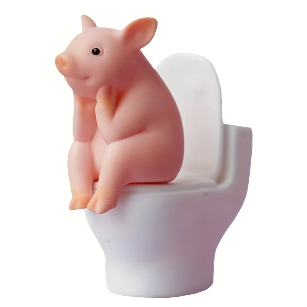 Studio shot of a pink pig figurine sitting on a miniature white toilet, isolated on a white background.