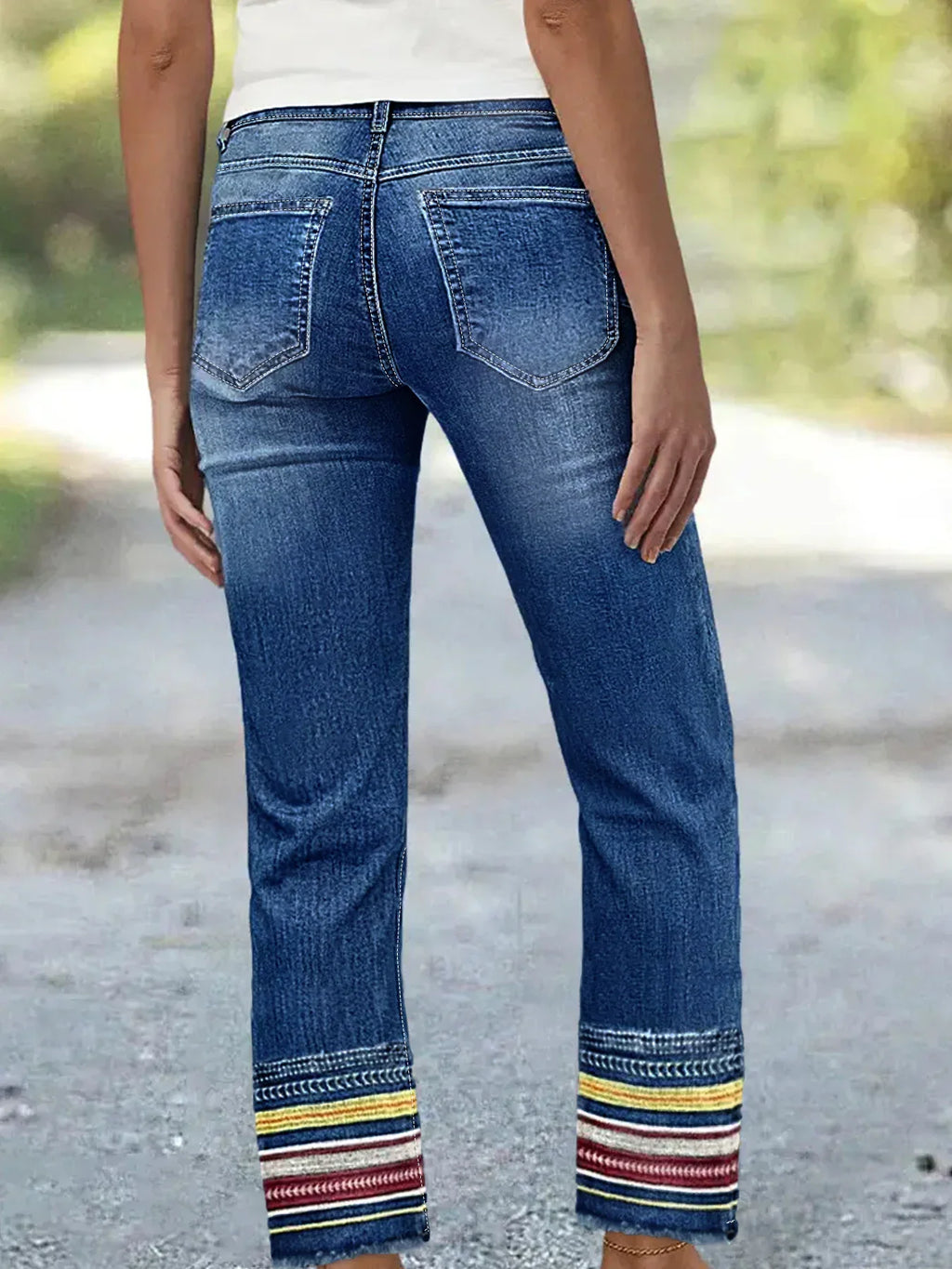 Back view of blue denim jeans with back pockets and embroidered cuffs