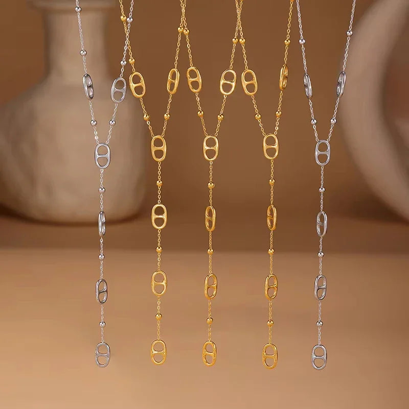 A collection of silver and gold-toned y-shaped necklaces with oval link accents hanging against a neutral background.