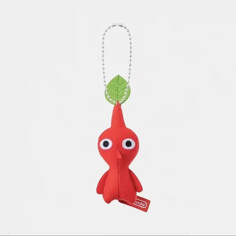 A small red plush doll keychain with a green leaf on its head