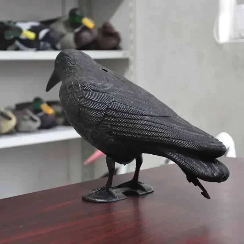 A black crow statue for bird repellent, side view, against a background of shelves.