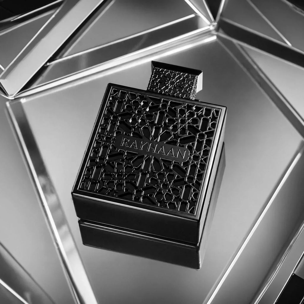Black ornamental perfume bottle with lattice design reflected on a metallic surface