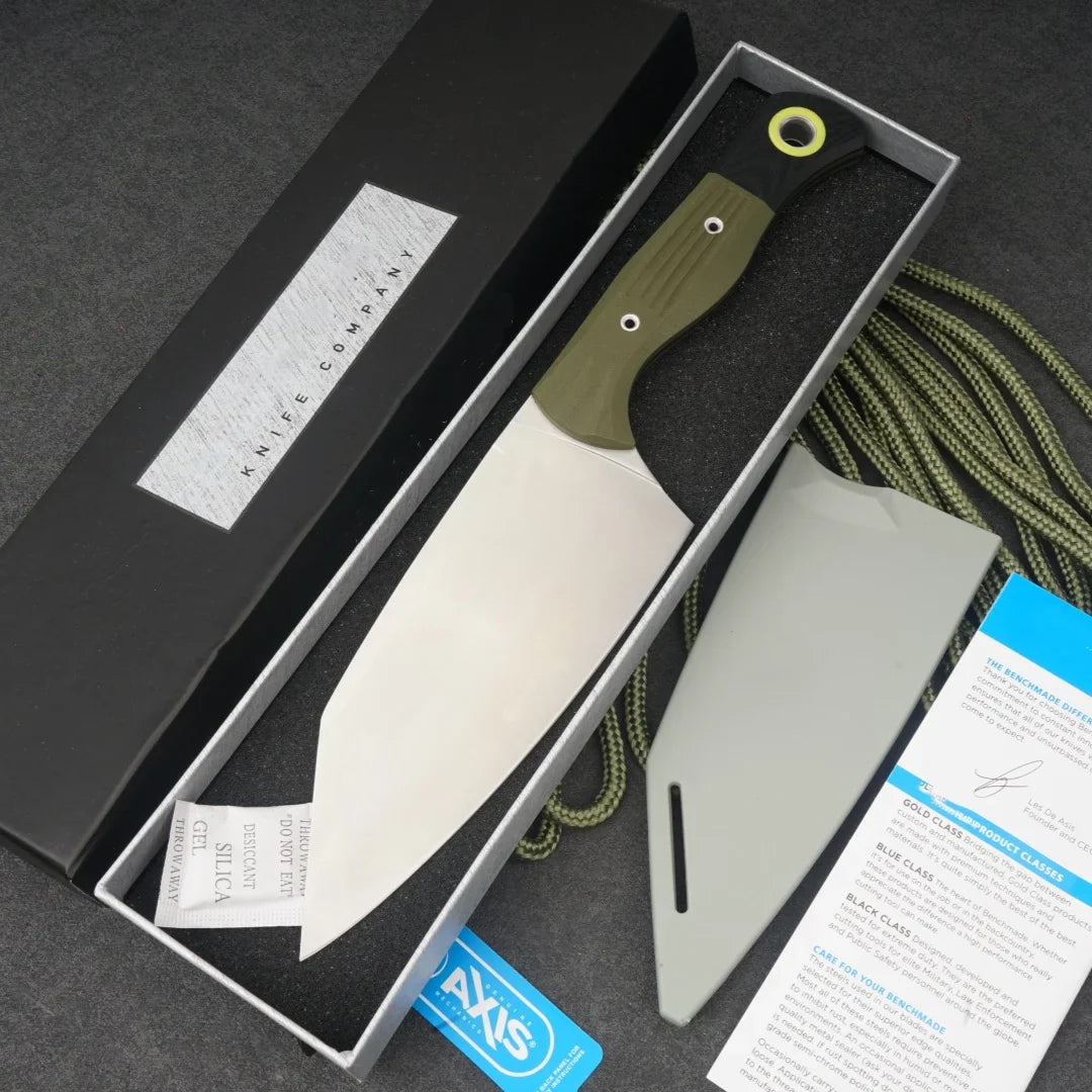 A stainless steel chef knife with an olive green and black micarta handle, inside its box with accessories.
