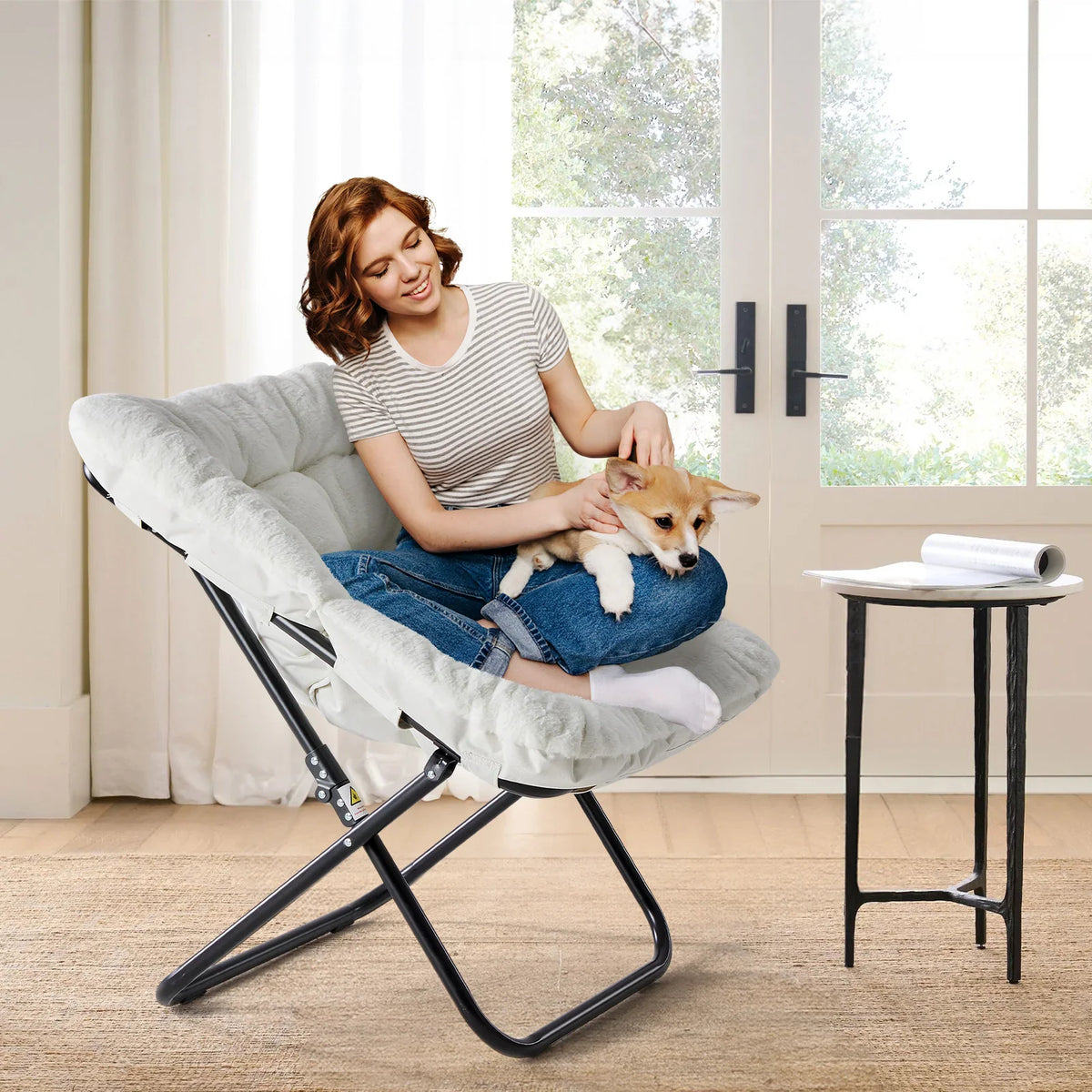 Woman sitting on a white faux fur saucer chair with a puppy