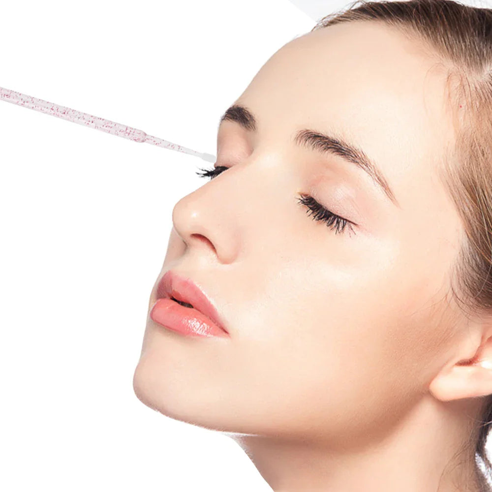A profile view of a woman having her eyelash extension area cleaned with a fine disposable microbrush.
