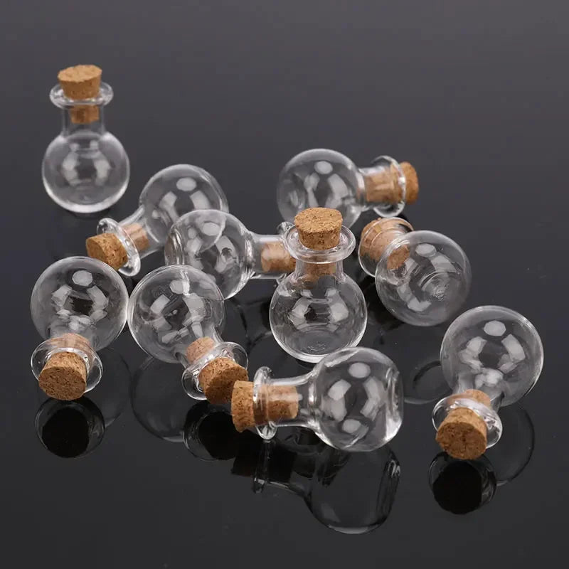 A group of small transparent round glass bottles with cork stoppers scattered on a reflective surface