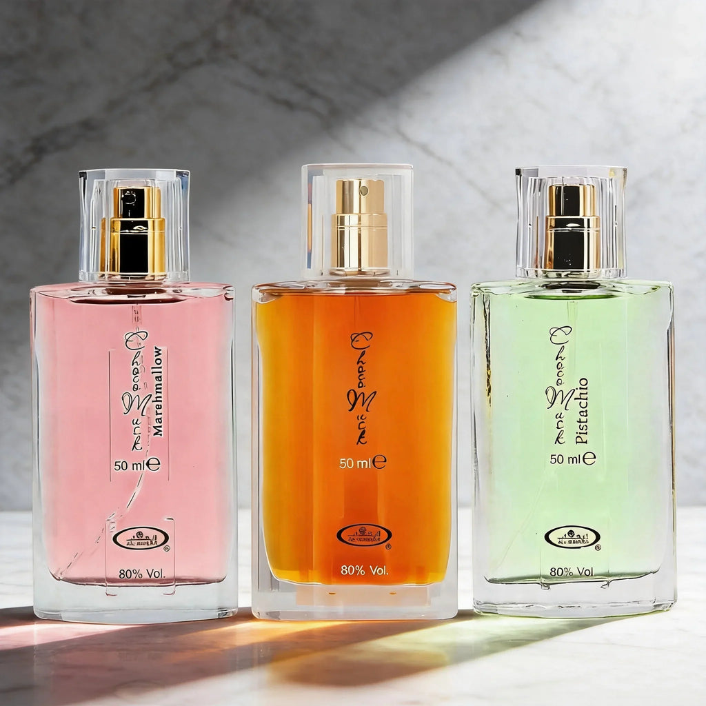 Trio of 50ml eau de parfum bottles in pink, orange, and light green on a marble surface with soft shadows.