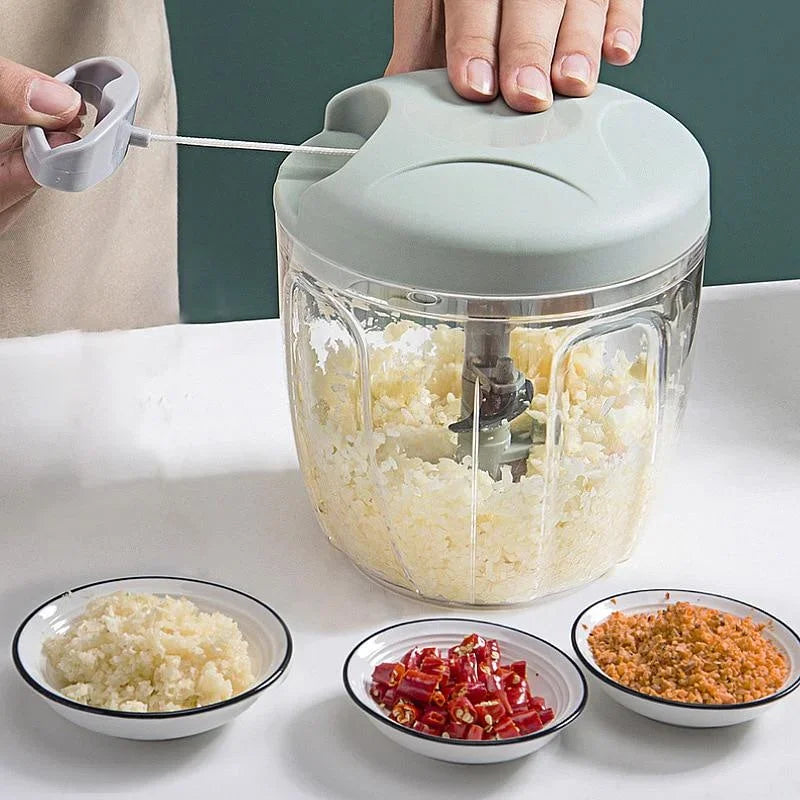 A green and transparent manual hand-pulled vegetable chopper with minced ingredients on a counter.