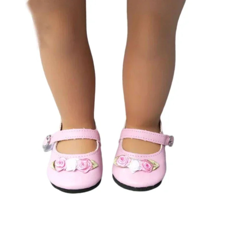 Pair of light pink doll Mary Jane shoes with rose details worn on doll legs