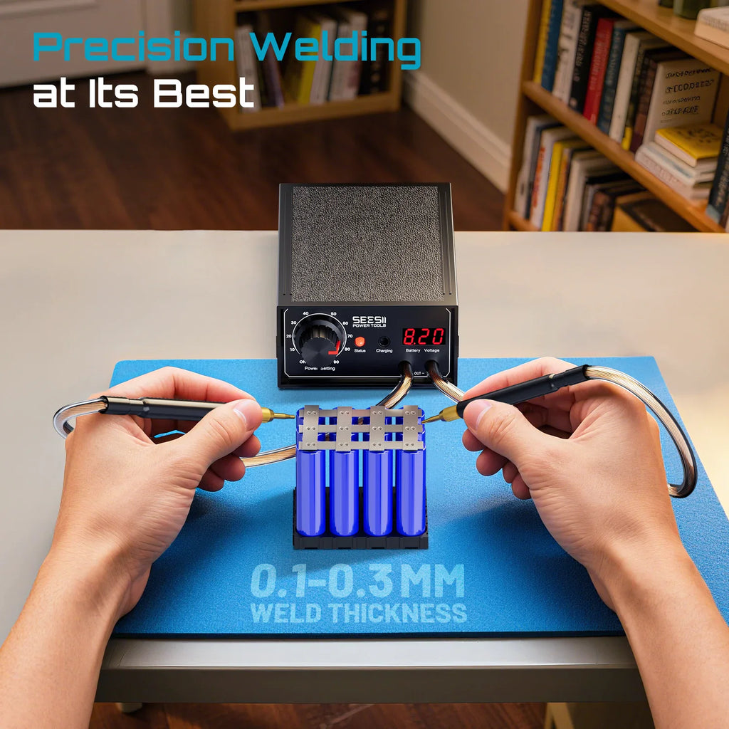Close-up of a person using a handheld spot welder to perform precision welding on battery cells.
