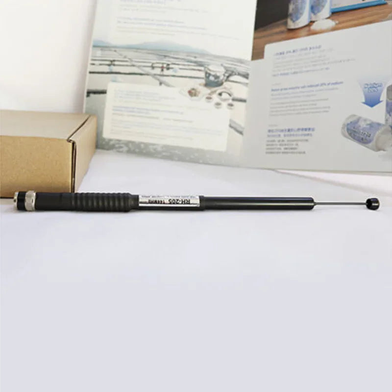 A black telescopic radio antenna extended in front of a printed document.