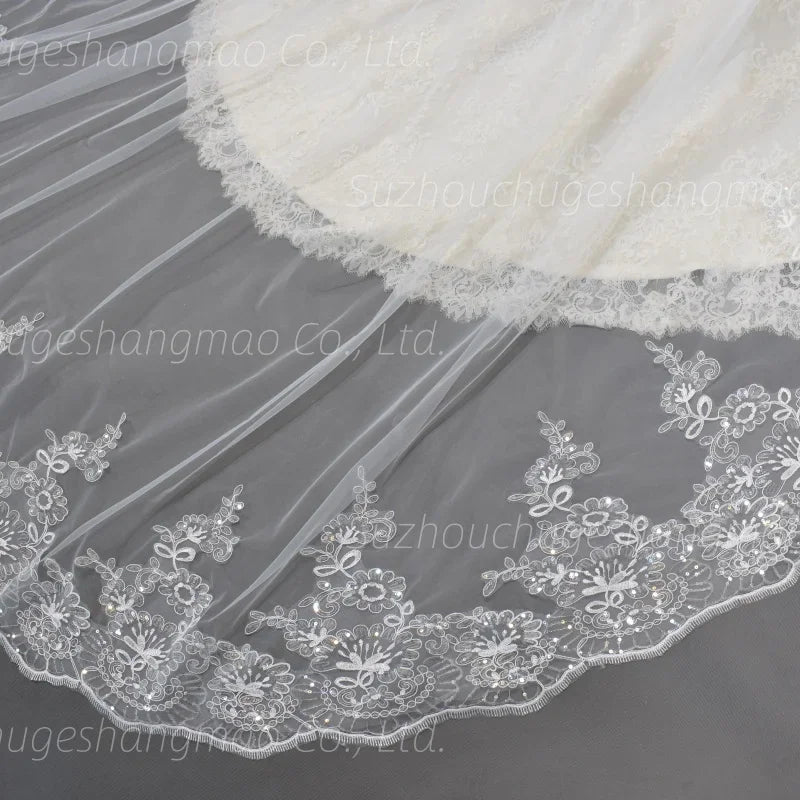 Detailed view of white tulle wedding veil edge with embroidered lace flowers and sequins