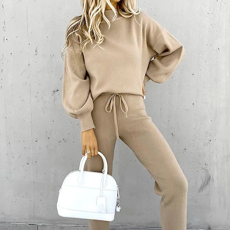Woman posing in a beige knitted long sleeve pullover and drawstring jogger pant set.