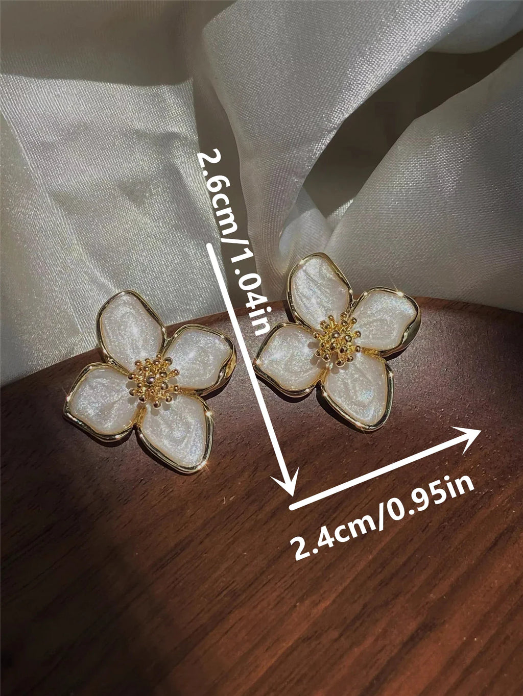 White floral stud earrings with gold trim and dimension labels