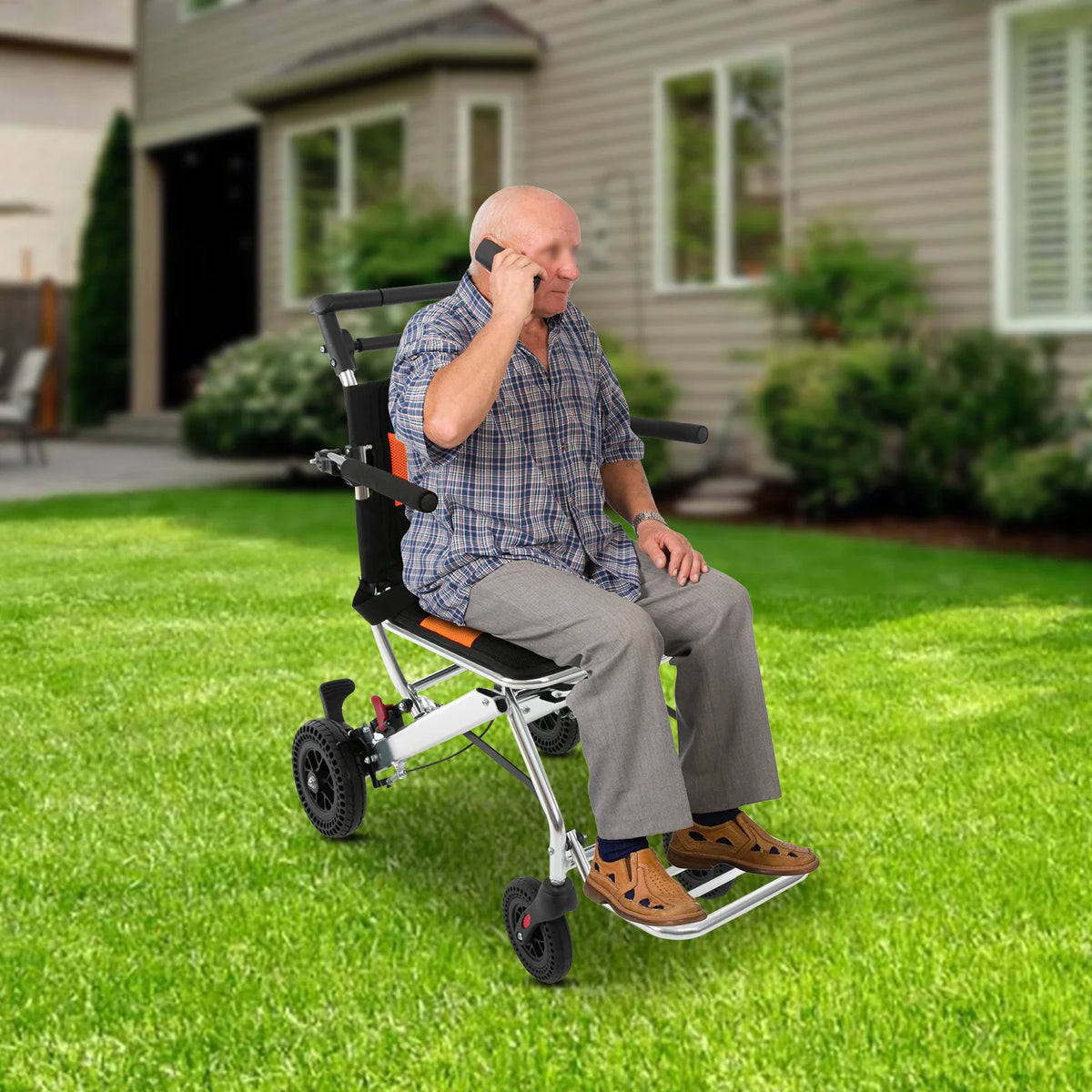 Senior man sitting on a folding transport chair outdoors on a lawn while talking on a phone