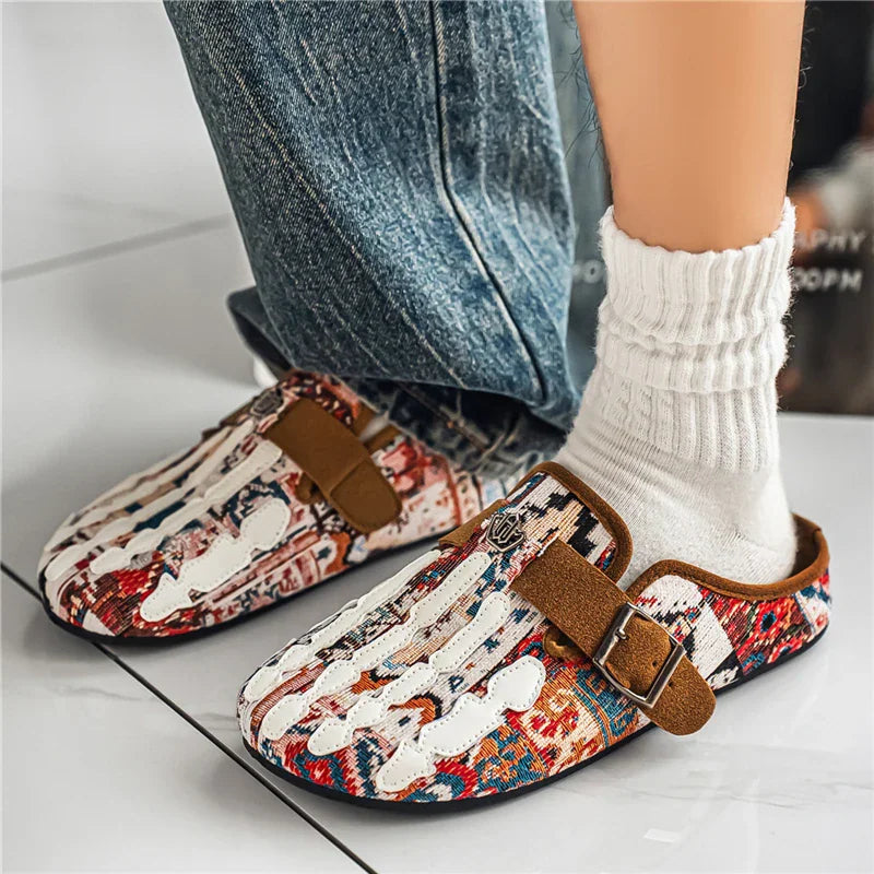 Men's slip-on mule shoes with a colorful pattern worn with white socks and blue jeans