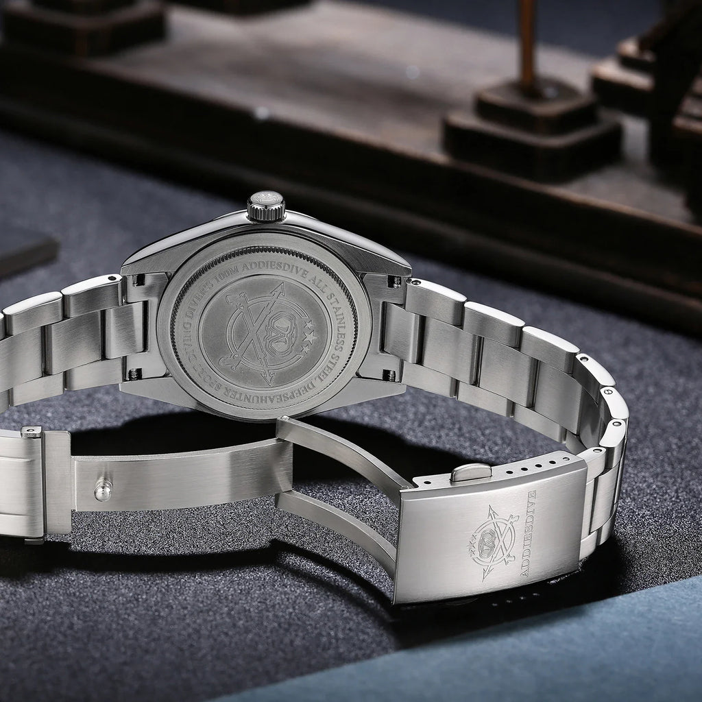 Back view of a stainless steel watch showing the engraved case back and deployment clasp